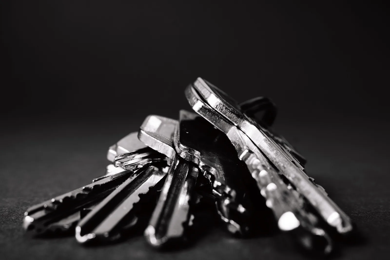 A pile of metal keys on a dark surface